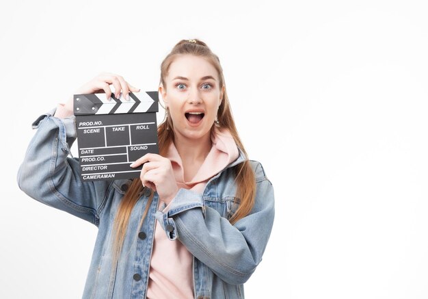 Young emotional woman holding a clapperboard on white background