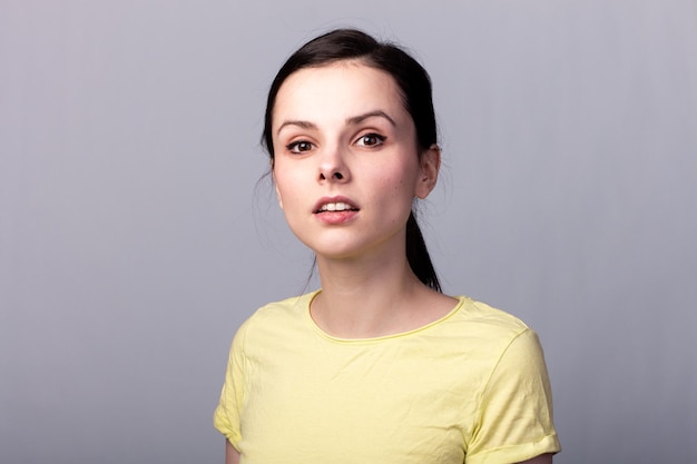 young emotional woman in a yellow tshirt on a gray background