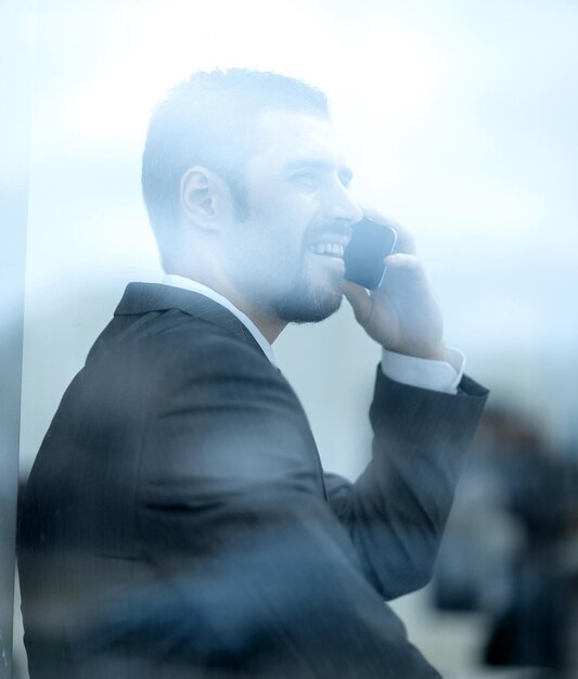 Foto giovane impiegato che parla al telefono seduto sul davanzale