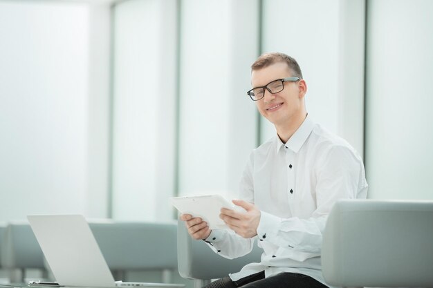 Young employee with a digital tablet sitting in a bright office