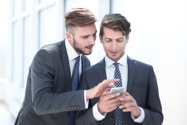 Young employees discussing media files on a smartphone