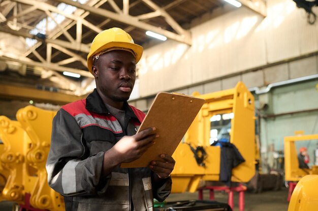 young engineer in hardhat and workwear looking through instruction points