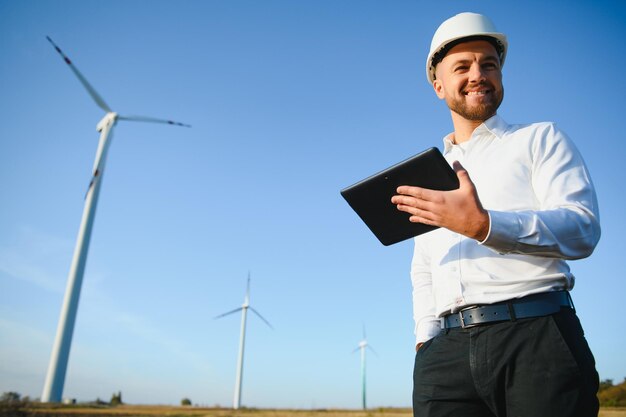 Foto giovane ingegnere che guarda e controlla le turbine eoliche sul campo