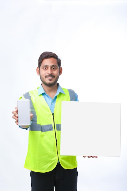 Молодой инженер показывает экран смартфона и пустую доску на белом фоне.