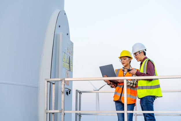 Young engineer team working with laptop computer against wind turbine farm