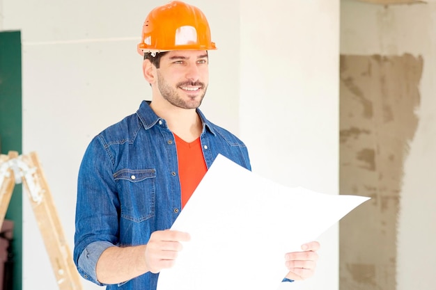 Young engineer with blueprint at construction site