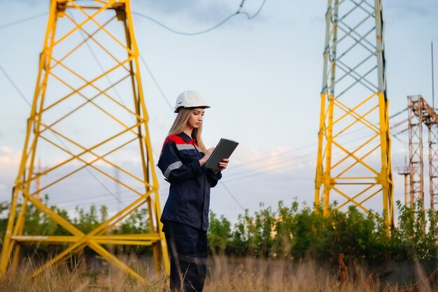 A young engineering worker inspects and controls the equipment of the power line. Energy.