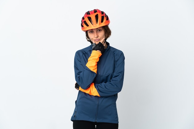 Young English cyclist woman isolated on white wall thinking