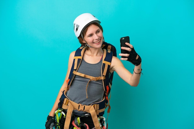 Young English rock climber woman isolated on blue background making a selfie