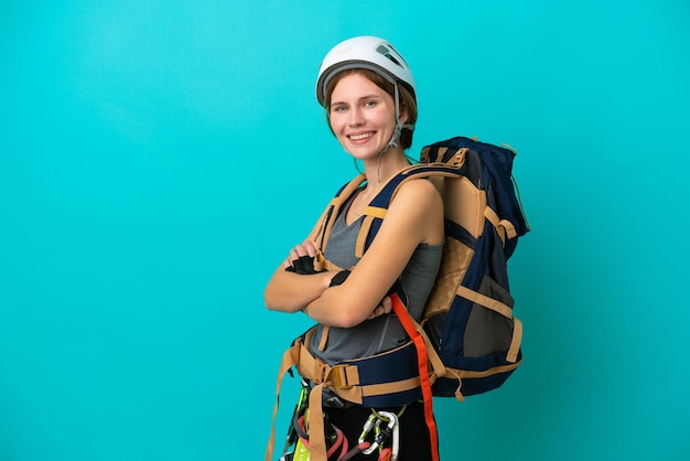 Young English rock climber woman isolated on blue background with arms crossed and looking forward