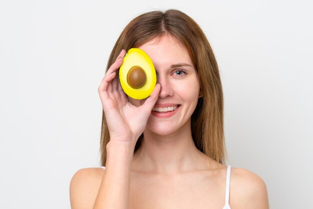 Young English woman holding an avocado while smiling Close up portrait