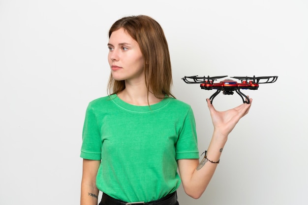 Young English woman holding a drone isolated on white background looking to the side