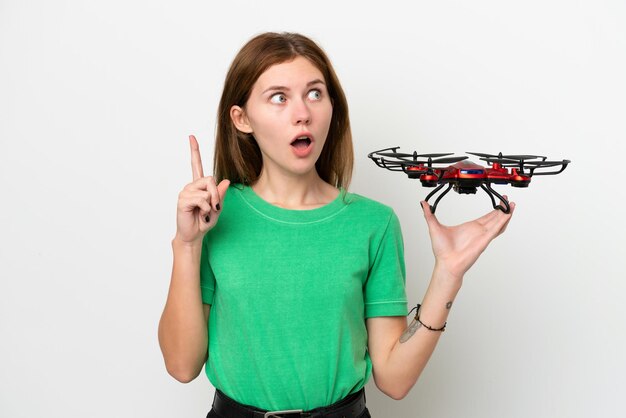 Young English woman holding a drone isolated on white background thinking an idea pointing the finger up