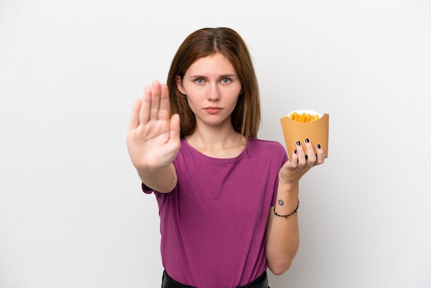 Foto giovane donna inglese che tiene patatine fritte isolate su sfondo bianco facendo un gesto di arresto