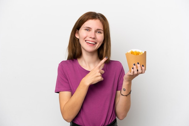 Young English woman holding fried chips isolated on white background pointing to the side to present a product