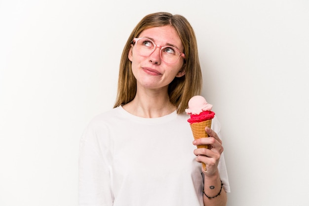 Young English woman holding an ice cream isolated on white background dreaming of achieving goals and purposes