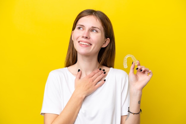 Young english woman holding invisible braces looking up while smiling