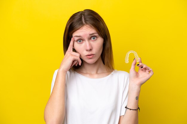 Young English woman holding invisible braces thinking an idea