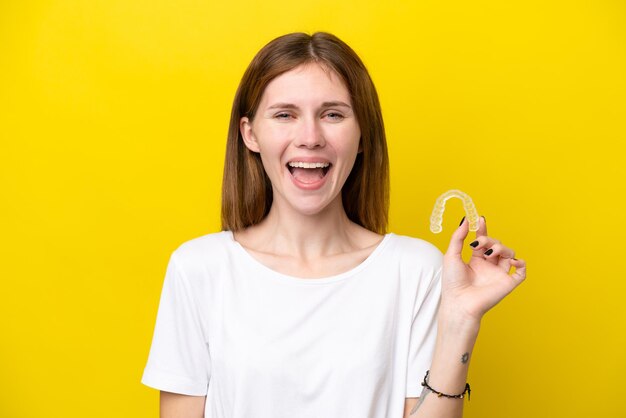 Young english woman holding invisible braces with surprise facial expression