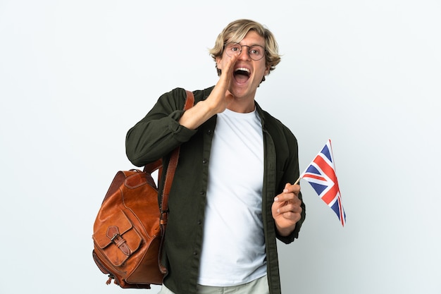 Young English woman holding an United Kingdom flag shouting with mouth wide open