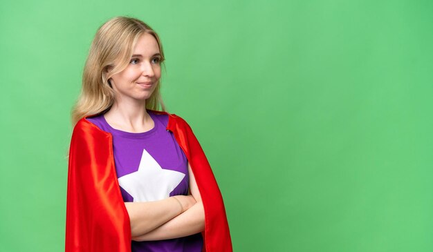 腕を組んでスーパー ヒーローの衣装で孤立した背景の上の若い英国人女性