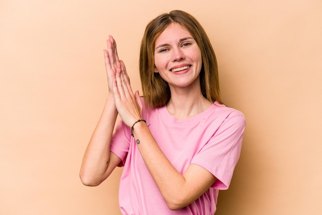 Young English woman isolated on beige background feeling energetic and comfortable rubbing hands confident