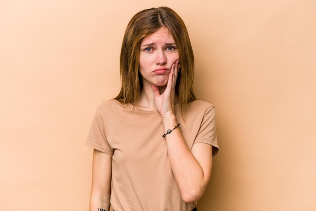 Young English woman isolated on beige background having a strong teeth pain molar ache