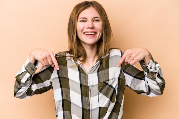 Photo young english woman isolated on beige background points down with fingers positive feeling