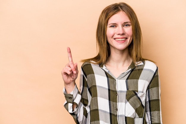 指でナンバーワンを示すベージュの背景に分離された若いイギリス人女性