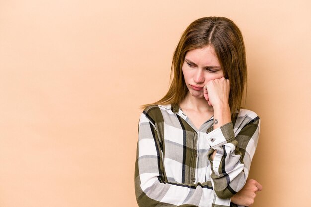 Young English woman isolated on beige background who feels sad and pensive looking at copy space