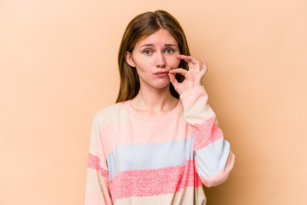 Photo young english woman isolated on beige background with fingers on lips keeping a secret.