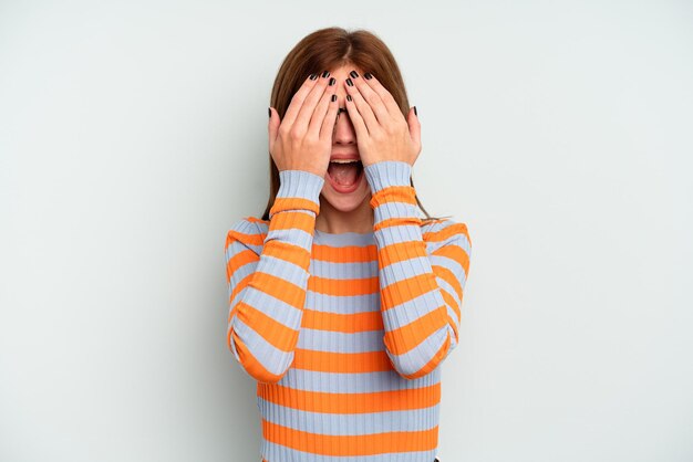 Young English woman isolated on blue background having fun covering half of face with palm.