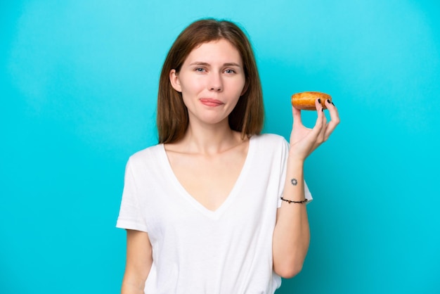 Young English woman isolated on blue background holding a donut