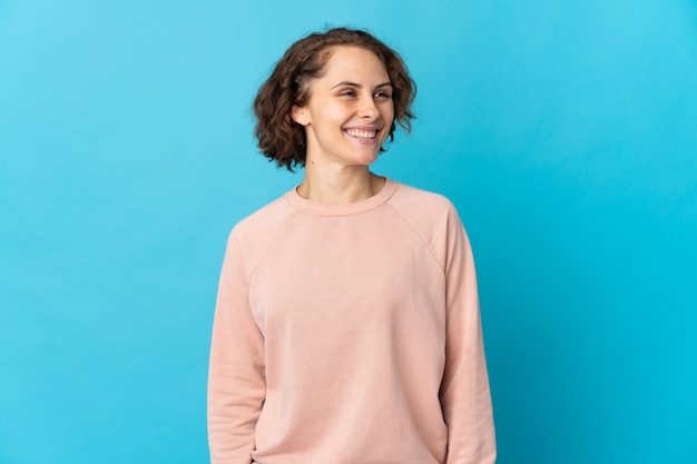 Young English woman isolated on blue background looking side