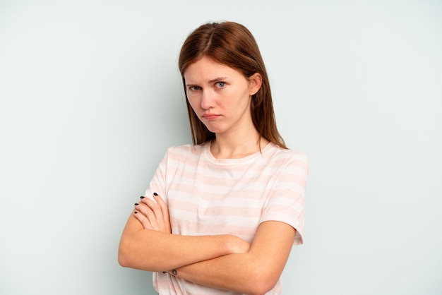 Young English woman isolated on blue background suspicious, uncertain, examining you.