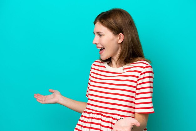 Young English woman isolated on blue background with surprise expression while looking side