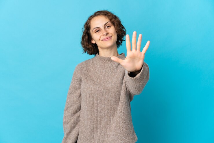 Photo 指で5を数える青い空間に孤立した若いイギリス人女性