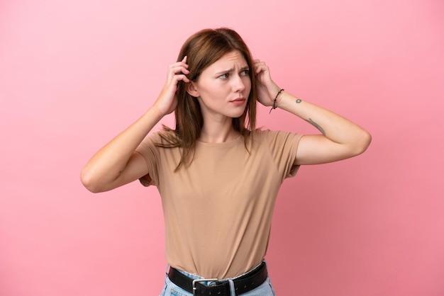 Giovane donna inglese isolata su sfondo rosa con dubbi e pensiero