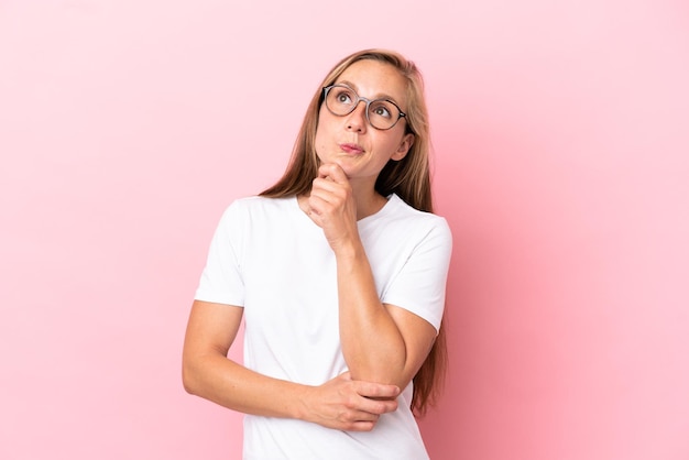 Young English woman isolated on pink background and looking up