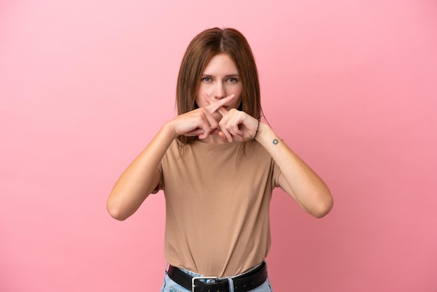 Young English woman isolated on pink background showing a sign of silence gesture