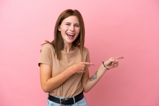 Young English woman isolated on pink background surprised and pointing side