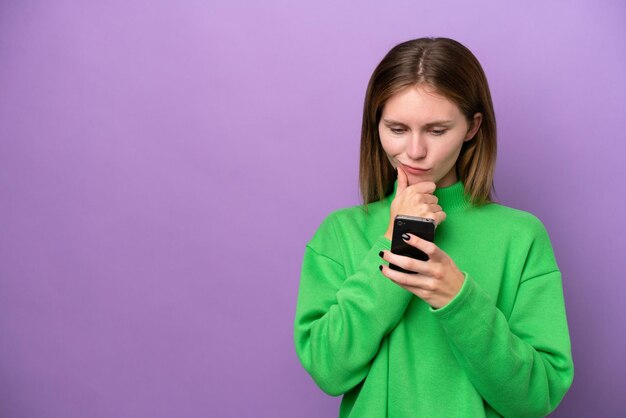 Young English woman isolated on purple background thinking and sending a message