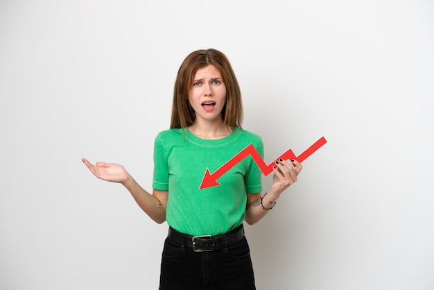 Young English woman isolated on white background holding a downward arrow and with sad expression