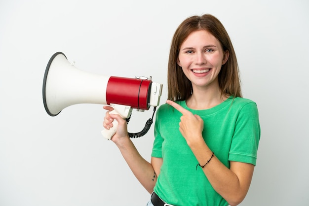 Young English woman isolated on white background holding a megaphone and pointing side