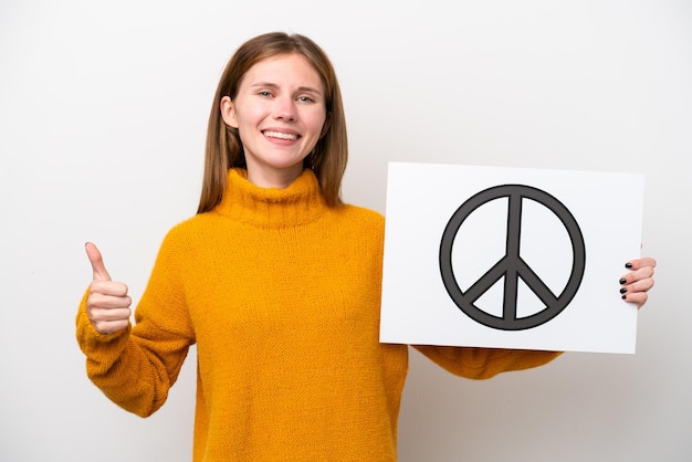 Young English woman isolated on white background holding a placard with peace symbol with thumb up