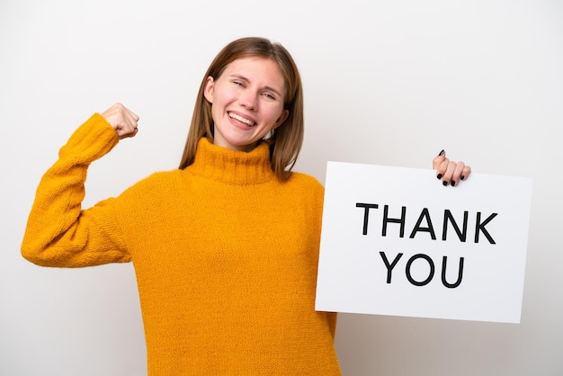 Young English woman isolated on white background holding a placard with text THANK YOU and doing strong gesture