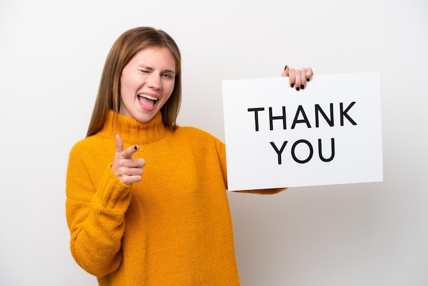 Young English woman isolated on white background holding a placard with text THANK YOU and pointing to the front