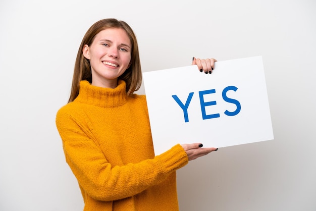 흰색 배경에 격리된 젊은 영국 여성, 행복한 표정으로 YES라는 문구가 적힌 플래카드를 들고