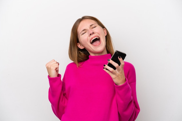 Photo young english woman isolated on white background with phone in victory position