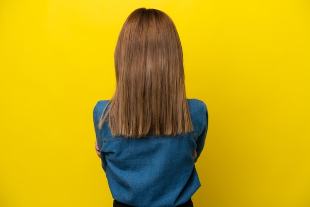 young english woman isolated on yellow background in back position